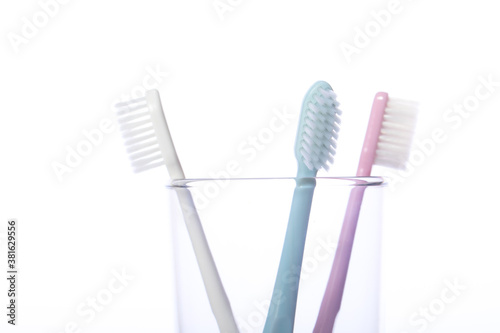 Close up view of three toothbrushes in transparent glass isolated on white background. Oral care  personal hygiene  healthy oral cavity  dental equipment  morning routine concept. Copy text space