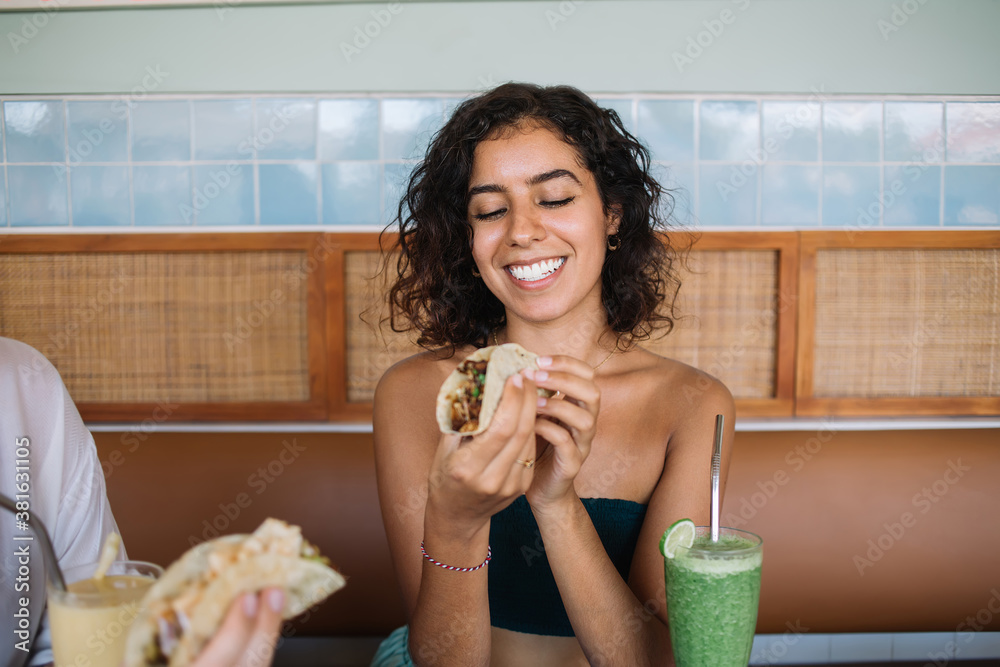 Happy young ethnic woman eating taco in cafe Happy young ethnic woman eating taco in cafe