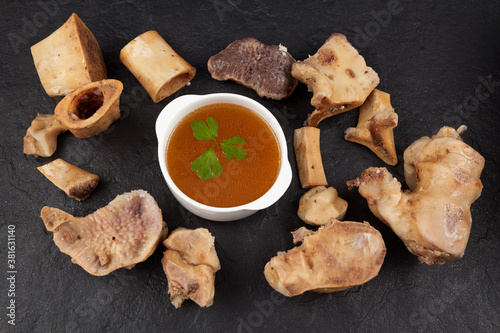 Homemade Beef Bone Broth in white bowl on a dark stone background. Bones contain collagen, which provides the body with amino acids, which are the building blocks of proteins