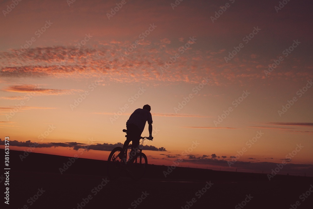 person riding a bike on the beach at sunset