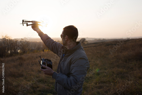 A man launches a drone into the sky. Drone operator with setting sun.