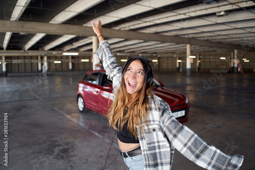 Young woman dancing and jumping in a parking lot.