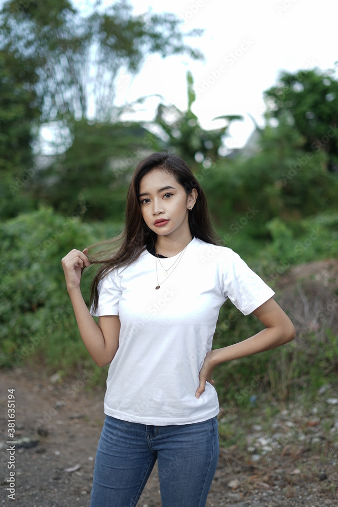 a stylish young woman wearing a white T-shirt against the backdrop of a forest view. black t-shirt models for mockups and templates.