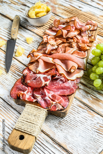 Set of cold cured italian meat Ham, prosciutto, pancetta, bacon. White wooden background. Top view