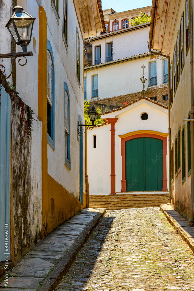 Fototapeta premium Alley with old houses and chapel in the background in the city of Ouro Preto in the state of Minas Gerais, Brazil