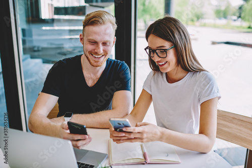 Caucasian male and female bloggers reading positive content publication during social networking on smartphone gadget, millennial connecting to 4g wireless for browsing website on cellular device