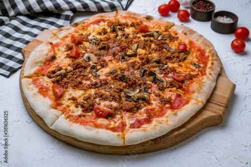 Italian meat pizza with mushrooms on white concrete table