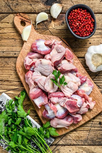 Raw uncooked Bird chicken giblets gizzards, stomachs on a cutting board. wooden background. Top view