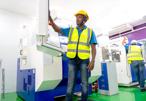 African American factory worker work with the machine in workplace area. Concept of good management system to support industrial business working. © narong