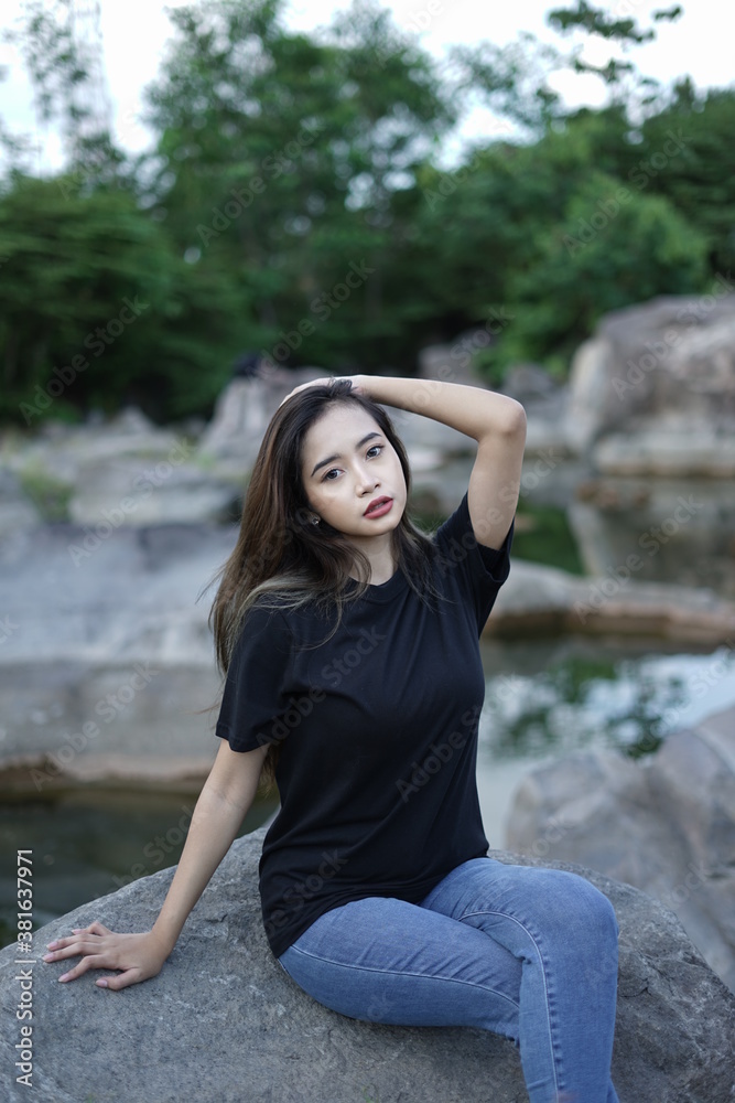 Stylish blonde girl wearing a black shirt with views of natural rocks, lake water and clear sky. female t-shirt models for mockups and templates. Stylish blonde girl wearing a black shirt with views of natural rocks, lake water and clear sky. female t-shirt models for mockups and templates.