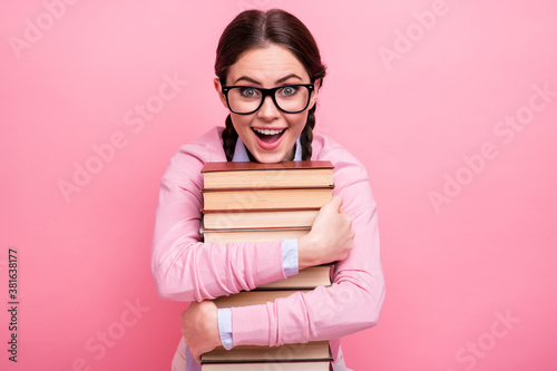 Close-up portrait of her she nice attractive pretty amazed cheerful cheery addicted genius brown-haired teenage girl embracing pile book science lover isolated on pink pastel color background photo