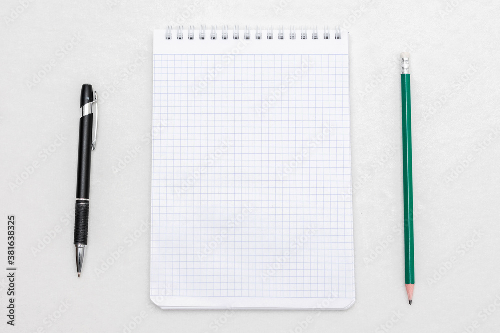 Spiral white notepad, ballpoint pen and pencil top view, white background, copy space
