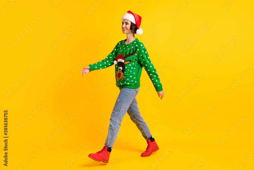 Full length profile side photo positive girl in santa claus headwear go walk copyspace x-mas christmas theme party wear deer decor sweater jeans boots isolated bright shine color background Full length profile side photo positive girl in santa claus headwear go walk copyspace x-mas christmas theme party wear deer decor sweater jeans boots isolated bright shine color background