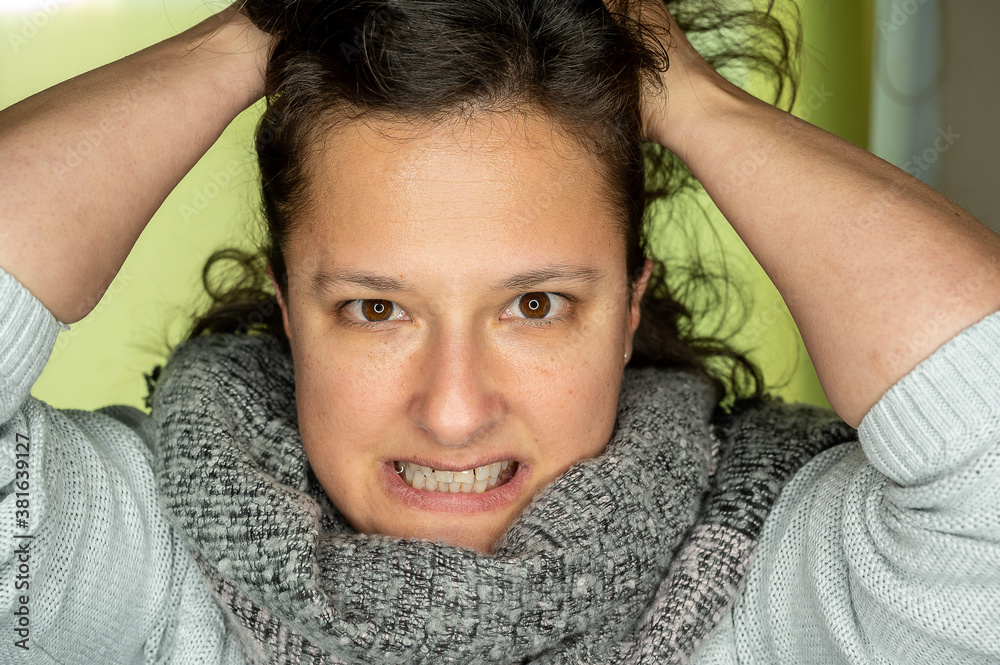 A young woman with an angry look is pulling her hair.