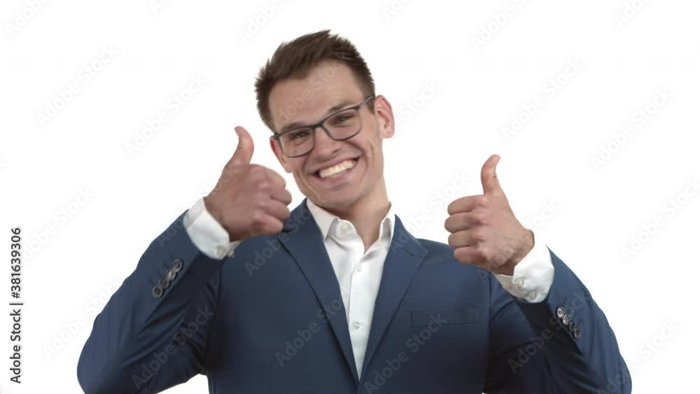 Young happy businessman in blue suit and glasses jumping from bottom, appear with thumbs-up and smiling, praising something very good, standing over white background Young happy businessman in blue suit and glasses jumping from bottom, appear with thumbs-up and smiling, praising something very good, standing over white background