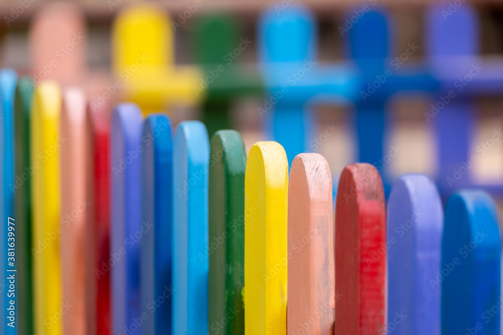 Part of wooden, rainbow colorful painted fence on a sunny hot summer day in a city park. Abstract multicolored background. Part of wooden, rainbow colorful painted fence on a sunny hot summer day in a city park. Abstract multicolored background.