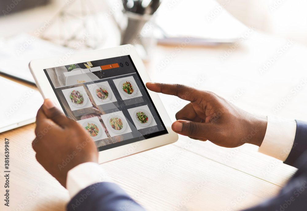 Fototapeta premium Black Businessman Using Tablet Ordering Food Online Sitting In Office