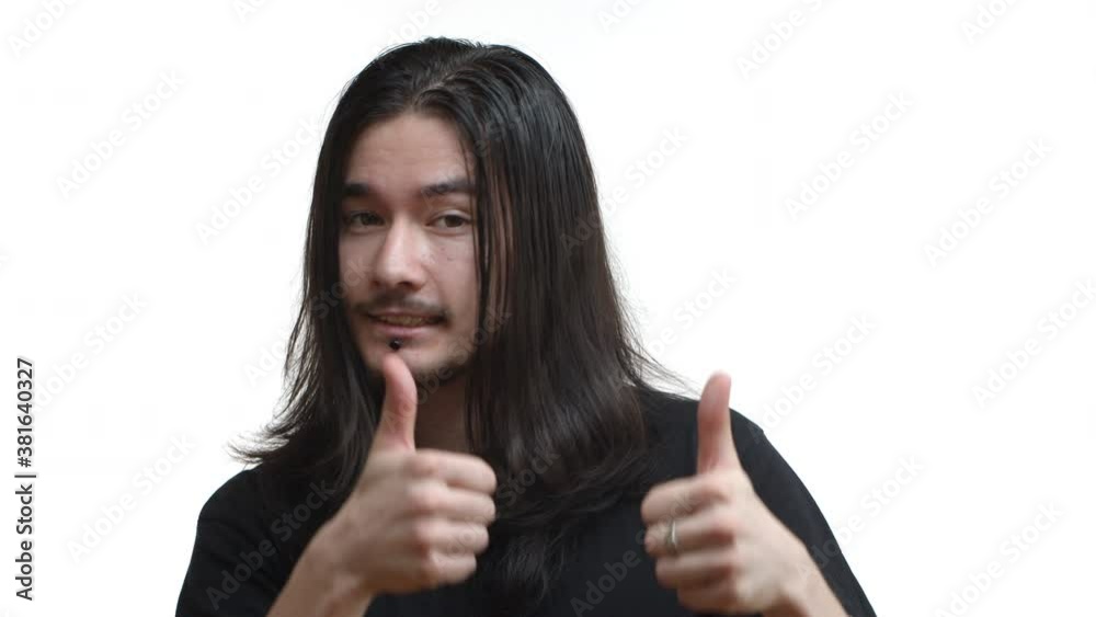 Close-up of east-asian male rocker, guy with piercing, long hair and moustache trying to smile while showing thumbs-up, approve or agree with something, standing over white background Close-up of east-asian male rocker, guy with piercing, long hair and moustache trying to smile while showing thumbs-up, approve or agree with something, standing over white background