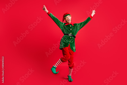 Full size photo of crazy elf dancing with raised fists wear costume headwear isolated on bright shine color background © deagreez