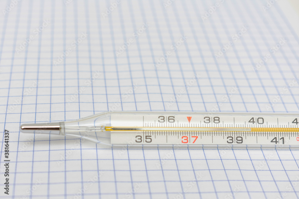 Mercury thermometer on a checkered paper, high body temperature, closeup Mercury thermometer on a checkered paper, high body temperature, closeup