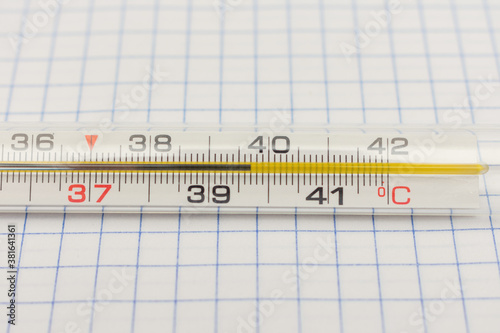 Mercury thermometer on a checkered paper, high body temperature, cropped image, close-up
