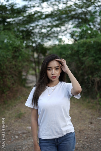 a stylish young woman wearing a white T-shirt against the backdrop of a forest view. black t-shirt models for mockups and templates.