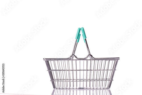 empty metal grocery basket for shopping in supermarket with raised handles and green plastic elements isolated on white background side view. Symbol of consumer society. Copy space for advertisement