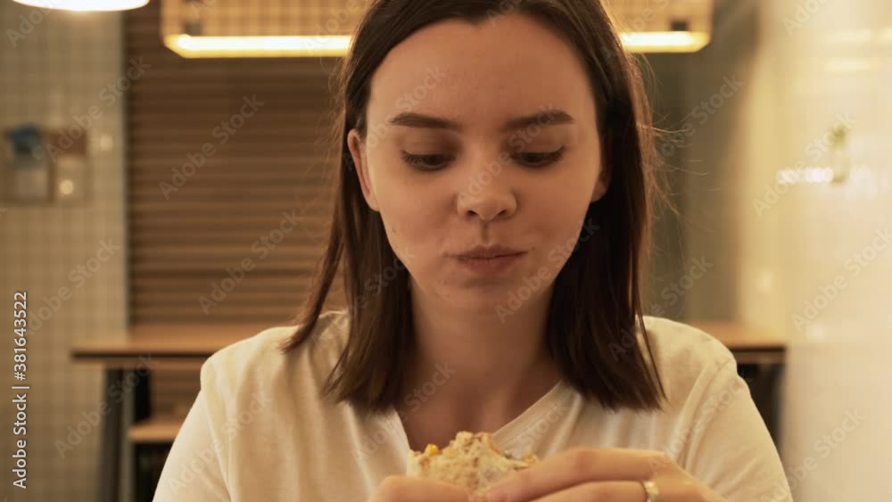 Young woman eats burrito. Girl eating wrap in restaurant, tasty chicken roll street food, girl bites unhealthy fast food close up Young woman eats burrito. Girl eating wrap in restaurant, tasty chicken roll street food, girl bites unhealthy fast food close up