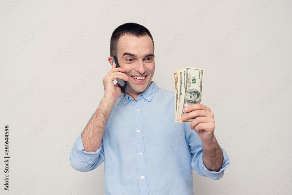 Cheerful man with a dollars talking on the phone, white background, copy space Cheerful man with a dollars talking on the phone, white background, copy space