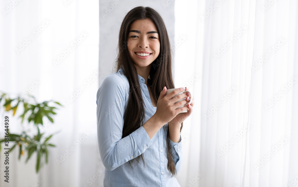 Morning Coffee. Smiling Korean Woman Enjoying Hot Drink Near Window At Home Morning Coffee. Smiling Korean Woman Enjoying Hot Drink Near Window At Home