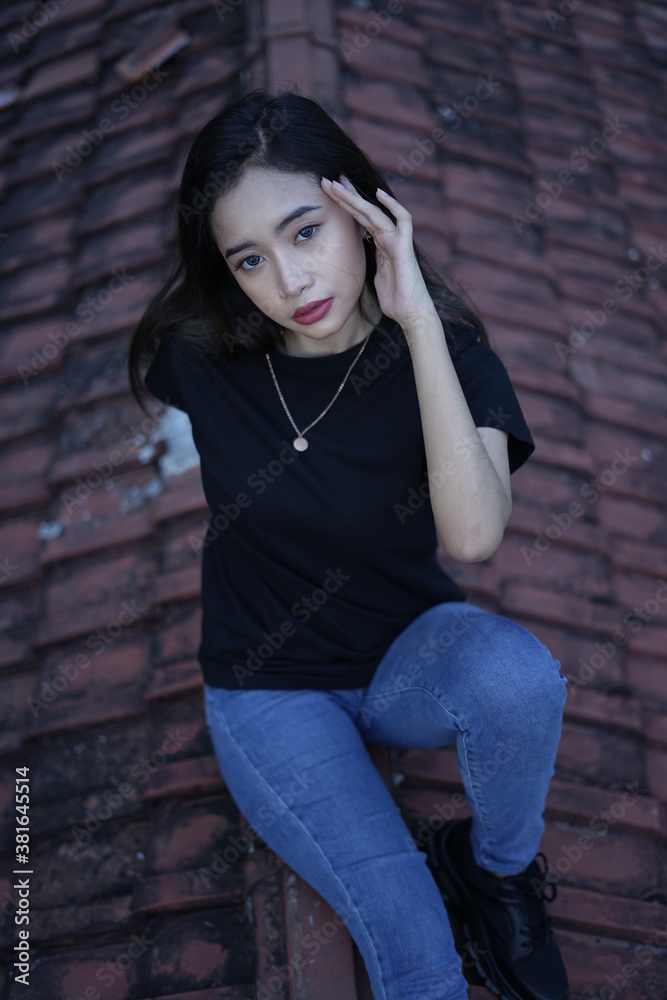 The blonde girl sits on the roof tile while stylish wearing a black t-shirt. female t-shirt models for mockups and templates. The blonde girl sits on the roof tile while stylish wearing a black t-shirt. female t-shirt models for mockups and templates.