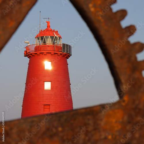 Poolbeg Red Lighthouse seen through the gear & cog of port crane in Dublin Port photo