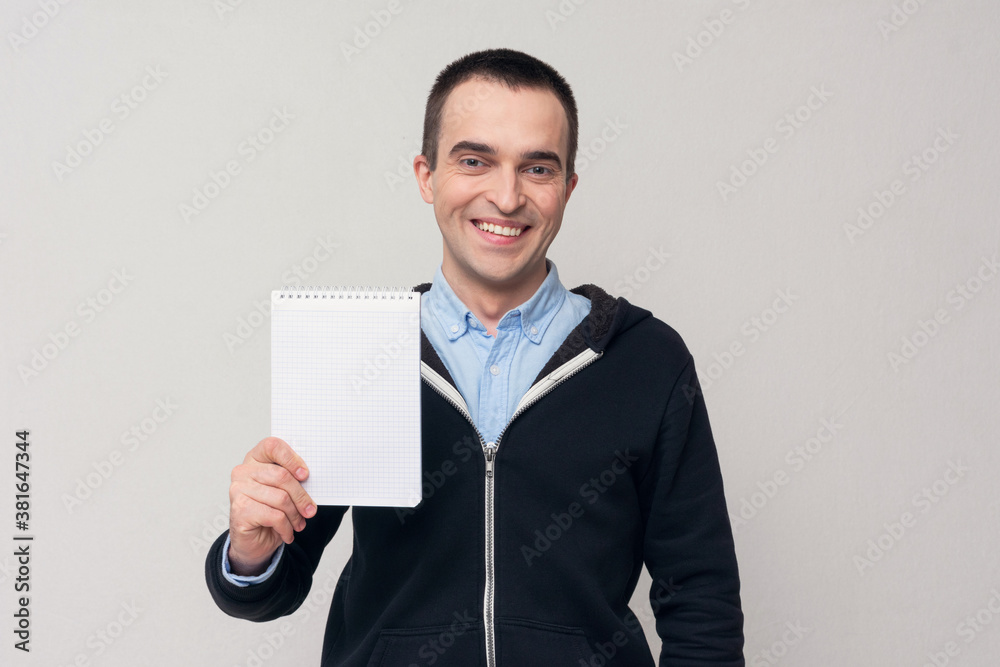 Happy man shows spiral notepad, white background, copy space Happy man shows spiral notepad, white background, copy space