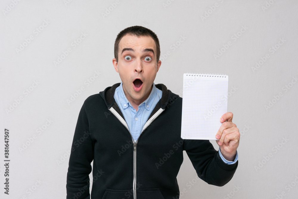 Stunned man shows notepad for notes, white background, copy space Stunned man shows notepad for notes, white background, copy space