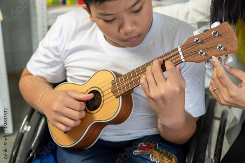 Beautiful teacher teaching students with disabilities to play the guitar.