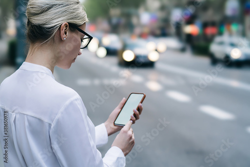 Crop focused young woman reading text message on smartphone while standing on roadside