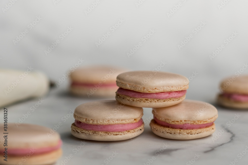 Fototapeta premium Homemade raspberry macarons stacked on white marble background. 