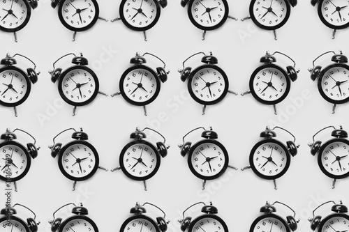 Pattern of many black alarm clocks isolated on white background.