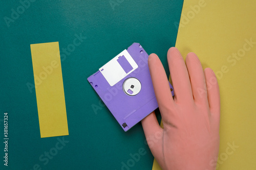 hand in pastel rubber glove with purple diskette on retro yellow colorful paper background
