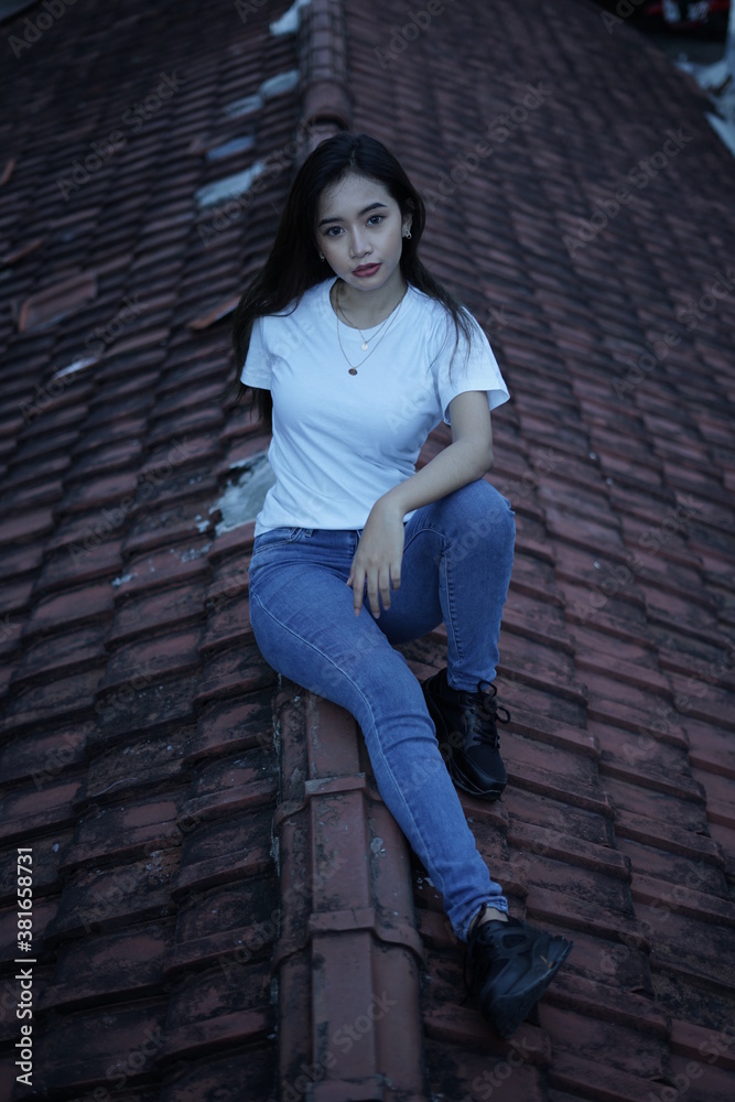 The blonde girl sits on the roof tile in a style wearing a white t-shirt. female t-shirt models for mockups and templates. The blonde girl sits on the roof tile in a style wearing a white t-shirt. female t-shirt models for mockups and templates.