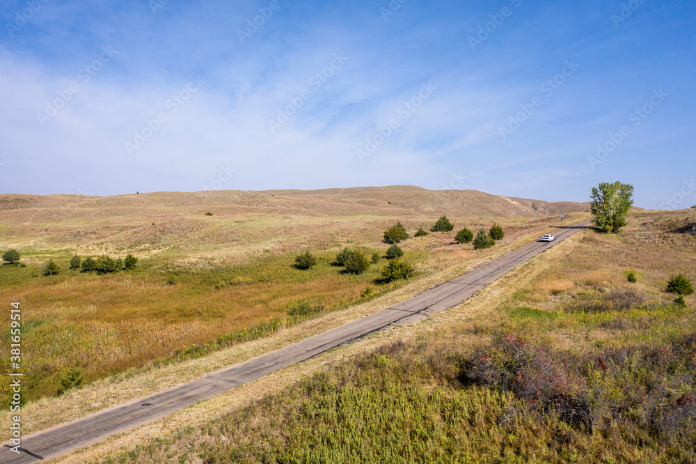 narrow rural highway in Nebraska Sandhills,  morning aerial view with a distant car
