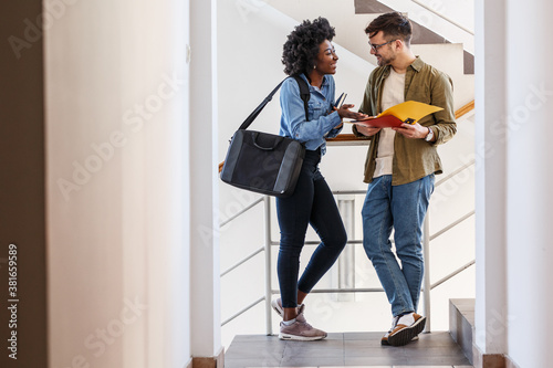 In the college lobby, a female and a male student engage in a lively conversation before their lecture, sharing insights and building connections in the vibrant atmosphere of learning.