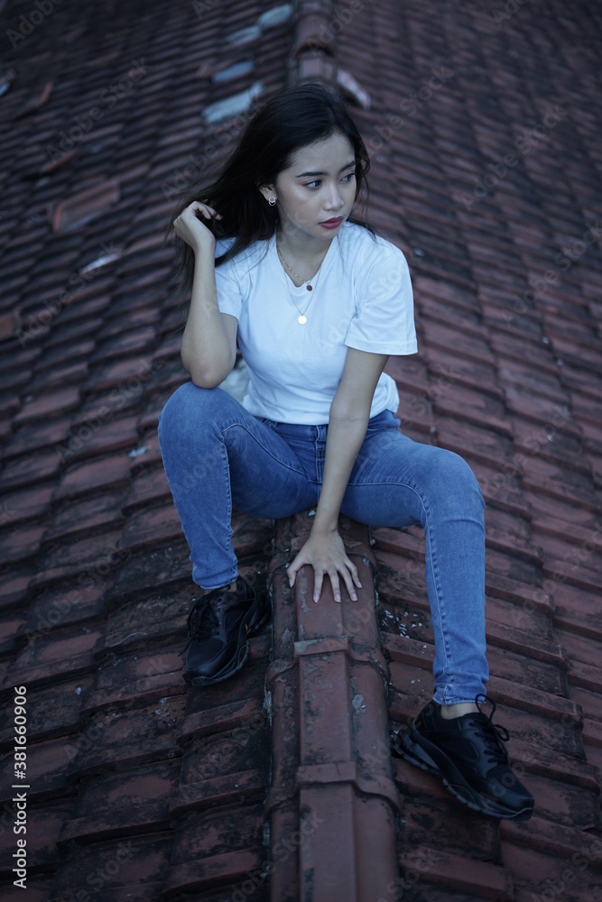 The blonde girl sits on the roof tile in a style wearing a white t-shirt. female t-shirt models for mockups and templates. The blonde girl sits on the roof tile in a style wearing a white t-shirt. female t-shirt models for mockups and templates.