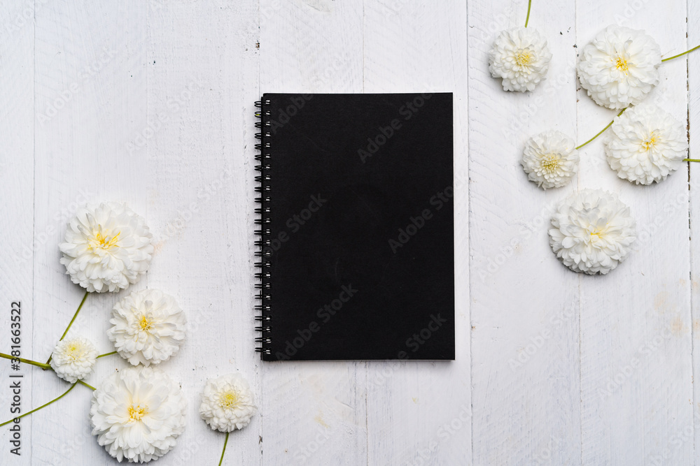 Obraz premium Notebooks and flowers-The book and white flowers on the white wooden table