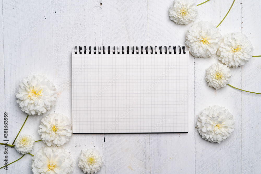 Obraz premium Notebooks and flowers-The book and white flowers on the white wooden table