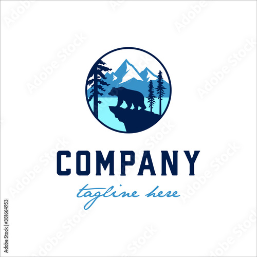 Bear stands on the edge of the lake with a few redwood trees