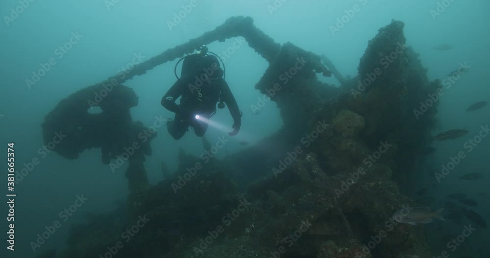 Scuba diver swims over decaying ship wreck.