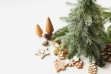 Christmas fir trees, gingerbread cookies, pine cones on white wooden background