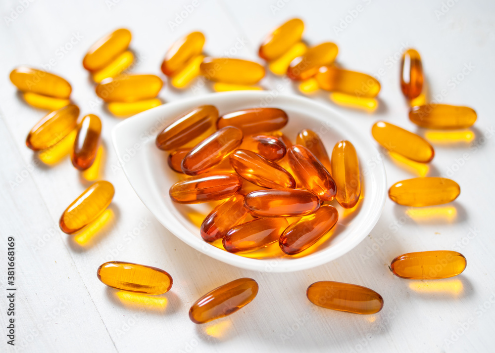 Fish oil capsules on white wooden background Fish oil capsules on white wooden background