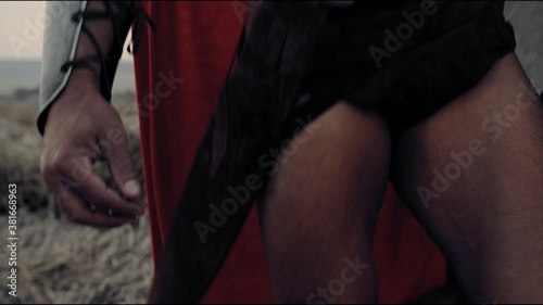 Unrecognizable spartan walking in field, sunset.